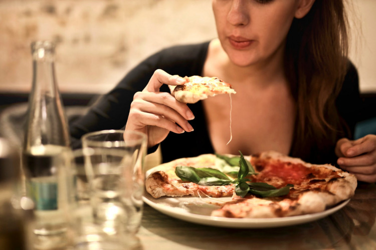 Woman Eats Alone As She Holds Sliced Pizza.