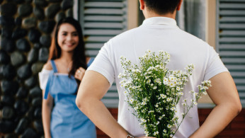 Man holding baby's-breath about to surprise a woman. 