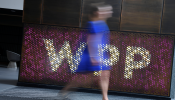 A woman walks past signage for WPP Group, the largest global advertising and public relations agency at their offices in London