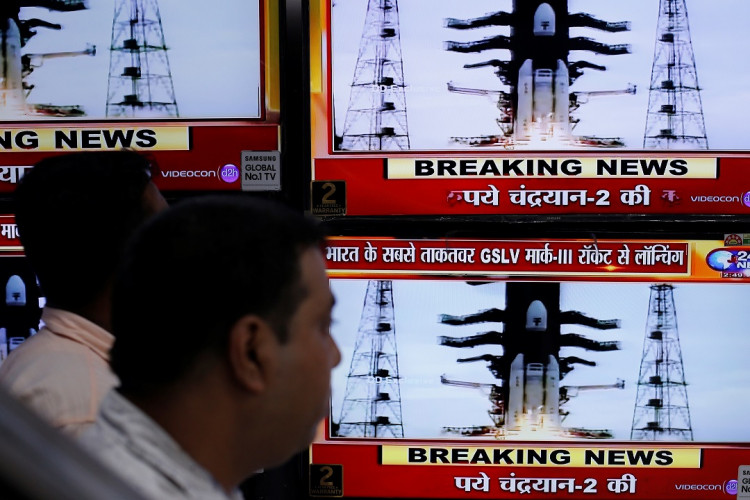 People watch a live broadcast of India's second lunar mission, Chandrayaan-2, inside an electronics showroom in Kolkata, India, July 22, 2019.