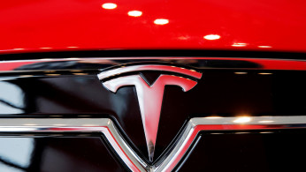 A Tesla logo on a Model S is photographed inside of a Tesla dealership in New York