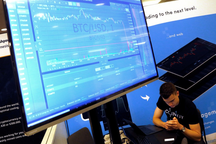  A man works beneath a display showing the market price of Bitcoin on the floor of the Consensus 2018 blockchain technology conference in New York City, New York, U.S., May 16, 2018.