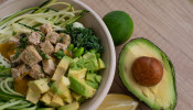 Bowl of salad with avocado on the side.