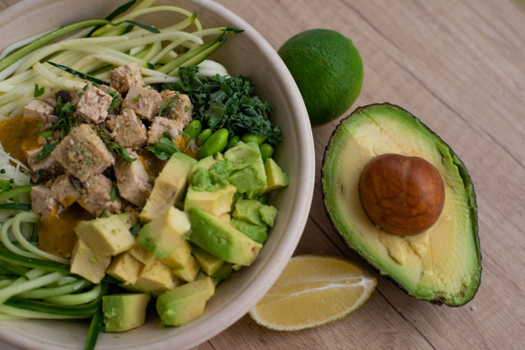 Bowl of salad with avocado on the side.