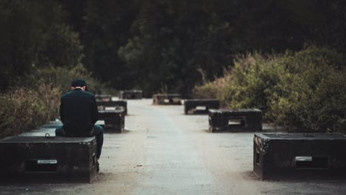 Man in black sitting on black concrete bench. 