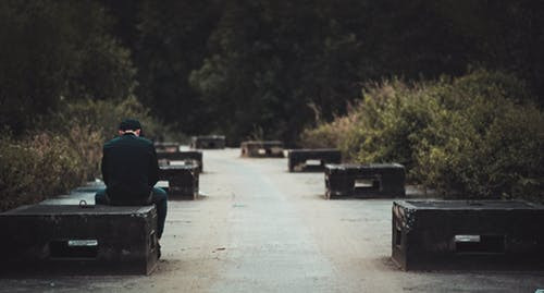 Man in black sitting on black concrete bench. 