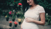 Close-up photo of pregnant woman in white dress.