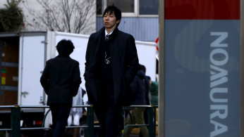 A man walks past a signboard of Nomura Securities outside its branch in Tokyo