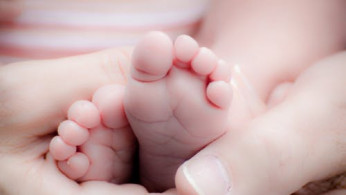 Person holding baby's feet.