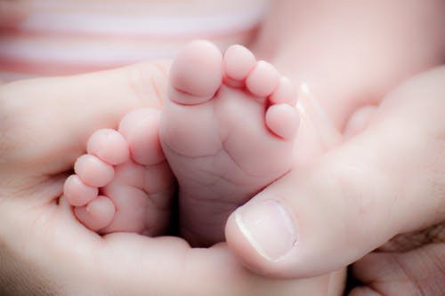 Person holding baby's feet.