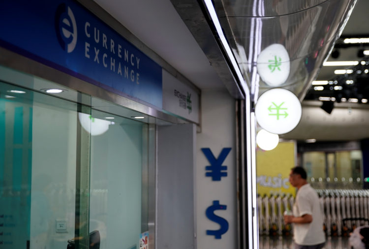 Signs of Chinese yuan and U.S. dollar are seen at a currency exchange store in Shanghai