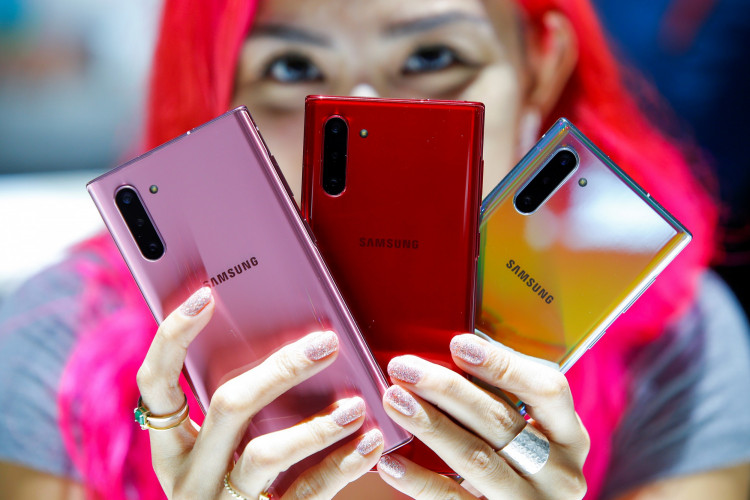 A woman holds different colored models of the Samsung Galaxy Note 10 while people test new devices during the launch event of the Galaxy Note 10 at the Barclays Center in Brooklyn