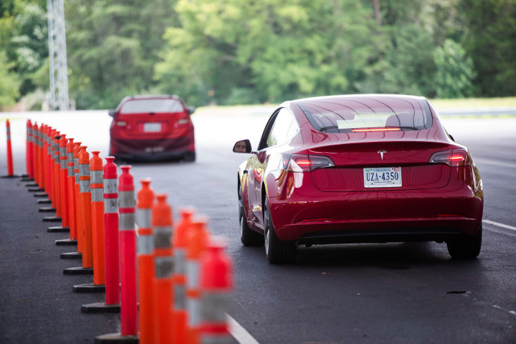 IIHS media relations associate Young demonstrates front crash prevention test on Tesla Model 3 at IIHS-HLDI Vehicle Research Center in Ruckersville, Virginia