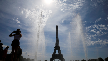 A woman enjoys a sunny and hot day at the Trocadero fountain in front of the Eiffel Tower in Paris