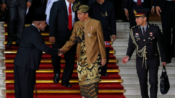 Indonesia's President Joko Widodo greets a parliament member as he departs after delivering address ahead of Independence Day at the parliament building in Jakarta