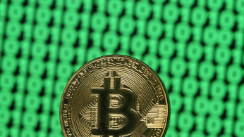 Bitcoin token is seen placed on a monitor that displays binary digits in this illustration picture