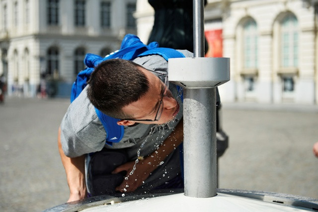 People drink water from a fountain on a hot summer day in Brussels