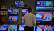 A salesman watches Prime Minister Narendra Modi addressing to the nation, on TV screens inside a showroom in Mumbai