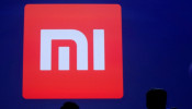 Attendants are silhouetted in front of Xiaomi's logo at a venue for the launch ceremony of Xiaomi's new smart phone Mi Max in Beijing, May 10, 2016. 