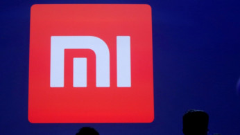 Attendants are silhouetted in front of Xiaomi's logo at a venue for the launch ceremony of Xiaomi's new smart phone Mi Max in Beijing, May 10, 2016. 