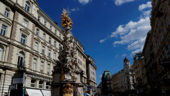 Tourists walk towards Holy Trinity column in Vienna