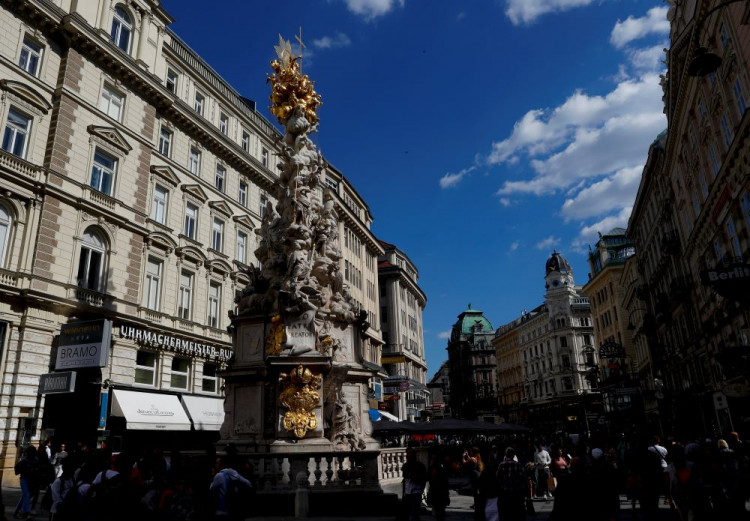Tourists walk towards Holy Trinity column in Vienna