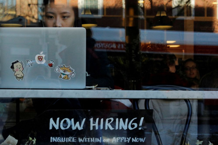 A "Now Hiring" sign sits in the window of Tatte Bakery and Cafe in Cambridge