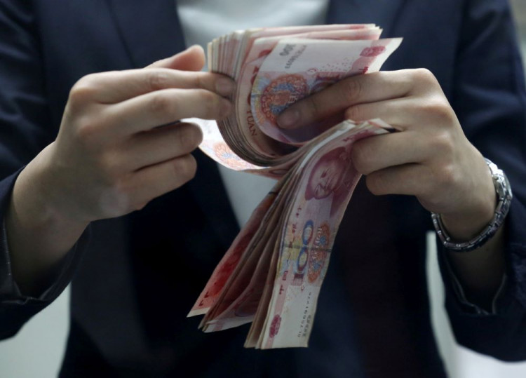 A clerk counts Chinese 100 yuan banknotes at a branch of a foreign bank in Beijing
