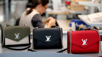 Louis Vuitton handbags are displayed as an employee works in a Vuitton new high-end garment factory in Beaulieu-sur-Layon