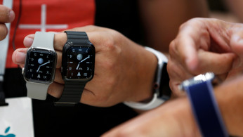 An attendee holds two titanium Apple Watch Edition smart watches in the demonstration area during a launch event at their headquarters in Cupertino